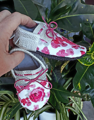 Silver leather moccs with short fringe and pink floral toe toppers.